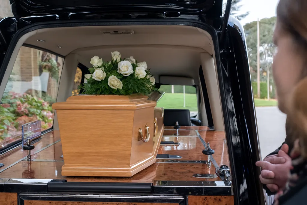 Cercueil en bois verni installé à l'intérieur d'un corbillard pour le transport funéraire