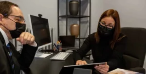 Entretien en bureau entre un conseiller funéraire et un client consultant une tablette.
