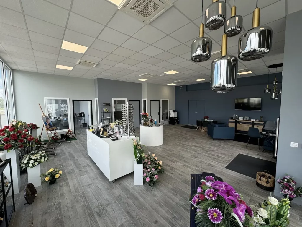 Grand espace d'accueil moderne avec fleurs, luminaires et comptoirs d'exposition.