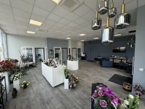 Grand espace d'accueil moderne avec fleurs, luminaires et comptoirs d'exposition.